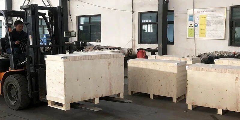 a forklift safely lifting a wooden crate using the designated slots in the base